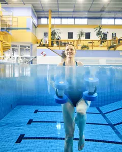 SWG-Frau-macht-Aquajogging Das Bild zeigt, wie eine Frau unter Wasser Aquajogging betreibt. Dabei sieht man ihren ganzen Körper und wie sie Aquahanteln in der Hand hält.